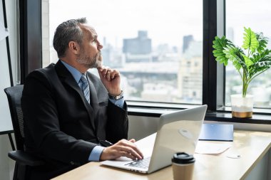 Kafkas kıdemli işadamı ofis işyerindeki masada çalışıyor. Çekici, olgun, olgun erkek çalışanlar şirket şirketinde özgüvenle oturup dizüstü bilgisayar yazıyorlar.