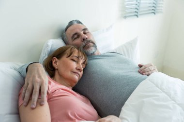 Kafkasyalı yaşlı çift, evde uyandıktan sonra yatağa uzanıyorlar. Çekici, yaşlı, pijamalı kadın ve erkek evdeki yatak odasında sabahın erken saatlerinde eğleniyorlar. Aile ilişkisi kavramı.