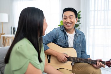 Asyalı çift boş zamanlarını birlikte oturma odasında geçiriyorlar. Çekici olgun erkek ve kadın kanepede oturuyor, sabahları gitar çalıp şarkı söylüyorlar. Etkinlik ilişkisi kavramı.