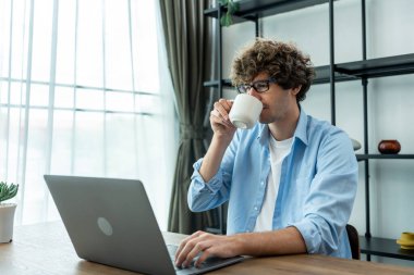 Kafkas işadamı evden çalışırken bir fincan kahve içiyor. Masada oturan yakışıklı serbest yazar dizüstü bilgisayarı kullanıyor. Oturma odasında online plan projesi yapıyor.