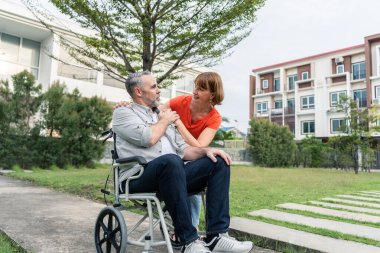 Kafkasyalı son sınıf öğrencisi kadın bahçede tekerlekli sandalyede kocasına destek oluyor. Çekici, olgun bir eş yaşlı bir hastayla ilgileniyor ve birlikte parkta fizik tedavi görüyor..