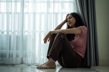 Asyalı genç üzgün kadın evde tek başına oturuyor. Çekici mutsuz kadın çok üzgün, yalnız ve hayal kırıklığına uğramış para borçlarını, bütçe kayıplarını, iflasları düşün.