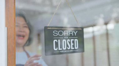 Asya kıdemli çifti dönüşüyor. Hoş geldiniz. COVID-19 tecridi ve karantinayı sona erdirdikten sonra, kafenin yeniden açılması için cam kapıya açık bir tabela koyduk. Büyükanne ve büyükbaba mutlu ve birbirlerine sarılıyorlar..