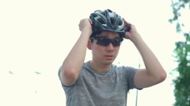 Halk parkında bisiklet süren Asyalı genç ve aktif erkek sporcu..