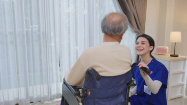 Asyalı genç kadın hemşire desteği engelli yaşlı adam tekerlekli sandalyede 
