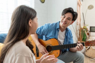 Asyalı genç çift boş zamanlarını birlikte oturma odasında geçiriyorlar. Çekici yeni evli erkek ve kadın yerde oturup sabahları gitar çalıp şarkı söylüyorlar. Evde etkinlik ilişkisi