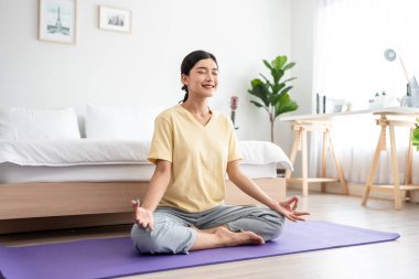 Asyalı genç ve güzel sporcu kadın evde yoga pilates yapıyor. Çekici kız egzersizi, egzersiz pozu nefes alma ve evde sağlık yaşam tarzı ve diyet için yoga ile meditasyon..