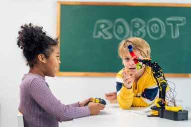 İlkokulda sınıfta öğrenen sevimli genç bir öğrenci. Genç okul çocuğu ve kız çocuğu mutlu ve rahatlar, masaya oturur ve kreşteki eğlenceli aktivitelerle kimya deneyi çalışırlar..