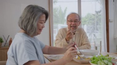 Mutlu Asyalı kıdemli yaşlılar emekli olur. Büyükbaba evde oturur, güler yüzle yemek masasında oturur. Olgun yaşlı erkek ve kadını seven aile fertleri rahatlayın evde sağlıklı yiyecekler yiyin.