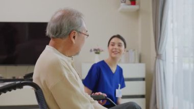 Asyalı genç kadın hemşire desteği engelli yaşlı adam tekerlekli sandalyede 