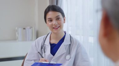 Asyalı yaşlı erkek hasta huzurevinde hekim hemşireyle konuşuyor..