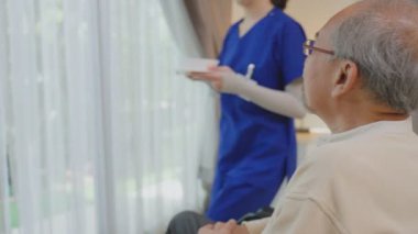 Sağlık merkezinin penceresinin yanındaki hastaya yardım eden hemşire.