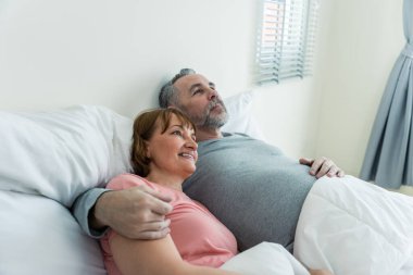 Kafkasyalı yaşlı çift, evde uyandıktan sonra yatağa uzanıyorlar. Çekici, yaşlı, pijamalı kadın ve erkek evdeki yatak odasında sabahın erken saatlerinde eğleniyorlar. Aile ilişkisi kavramı.