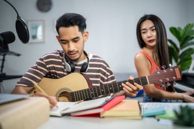 Asyalı bir arkadaşım gitar çalıyor ve evde elektronik film müzikleri yapıyor. Müzik stüdyosunda müzik aleti ve ses ekipmanı kullanarak yeni bir şarkı besteleyen çekici genç müzisyen..