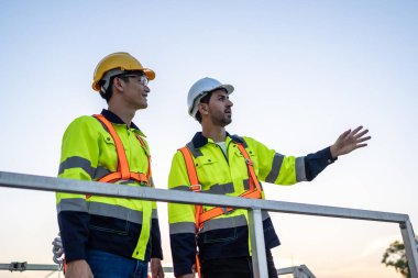 Açık hava deposunda çalışan çeşitli erkek teknisyenler. Yenilik mühendisi güvenlik donanımı giyen adamlar depo fabrikasının dışında çevresel yenilenebilir temiz enerji geliştirmek için çalışıyorlar..