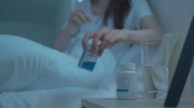 Yatakta uyumadan önce pijamalı hasta kızın yanına git. Çekici, güzel genç bir kadın mutsuz ve gecenin karanlığında evdeki yatak odasında öksürüyor. Sağlık-Tıbbi Yaşam Tarzları Konsepti.