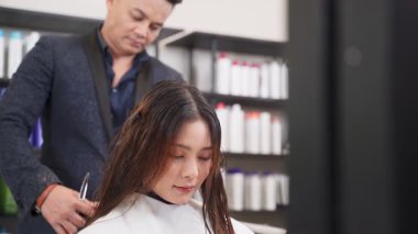 Bir güzellik salonunda saç kesen genç bir kadın.