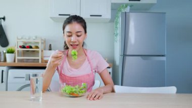 Modern mutfak ortamında taze salata yiyen kadın.