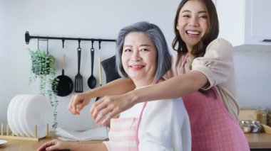 Gülümseyen kadınlar modern mutfakta birlikte yemek pişiriyorlar.