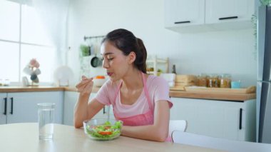 Modern mutfakta sağlıklı salata yiyen bir kadın.