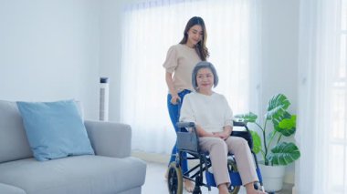 İçeride tekerlekli sandalyede yaşlı bir kadına yardım eden kadın.