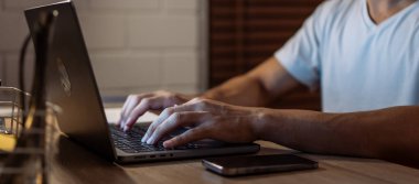 Geceleri masasında tek başına çalışan genç adama yaklaş. Çekici iş adamı, evde yatmadan önce bilgisayarını kullanarak dijital ekranlara bakıyor..