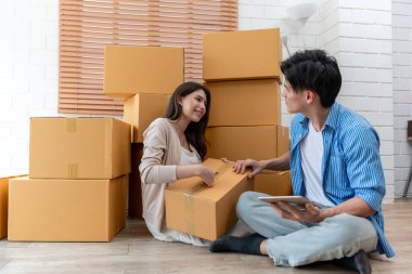 Asyalı genç çift yeni eve taşınan anıları olan eşyaları topluyor. Çekici bir adam ve kadın yeni bir yerde mutlu bir şekilde kutuları tutuyorlar. Ev taşıma konsepti.