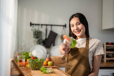 Evdeki mutfakta Vietnam böreği yiyen kadın portresi. Önlük giyen çekici, güzel bir kız. Sabahları evdeki sağlık için temiz aperatifler yiyor. Diyet ve Sağlıklı Yemek Konsepti