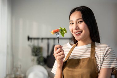 Evdeki mutfakta Vietnam böreği yiyen kadın portresi. Önlük giyen çekici, güzel bir kız. Sabahları evdeki sağlık için temiz aperatifler yiyor. Diyet ve Sağlıklı Yemek Konsepti