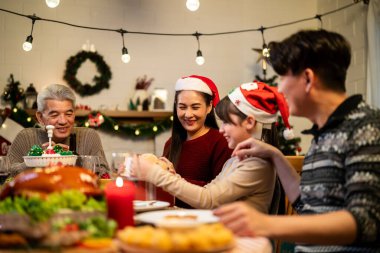 Asyalı sevimli aile Noel partisini evde kutluyor. Çekici ebeveynler ve akrabalar Şükran Günü 'nü kutlamak için yemek yiyorlar. Noel arifesi evde yemek masasında..