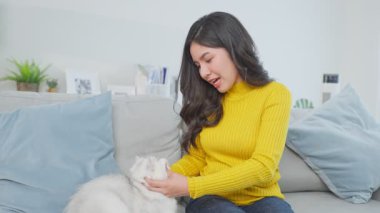 Genç bir kadın evcil hayvanıyla kanepede oturuyor..