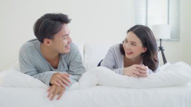 Genç adam ve kadın yatakta birlikte gülüyorlar.