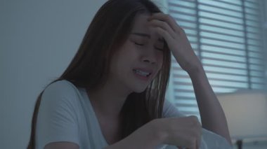 Kadın yatakta oturuyor, odada ağlıyor..