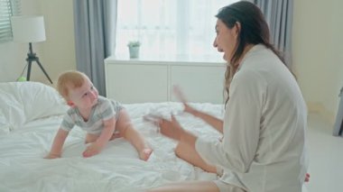 Evde yatakta bebekle oynayan bir kadın