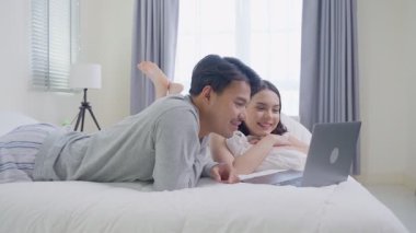 Çift yatak odasında dizüstü bilgisayar kullanarak rahatlıyor.