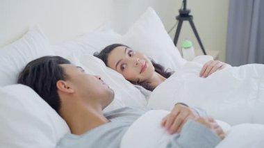 Yatakta uzanmış birbirine bakan bir çift.