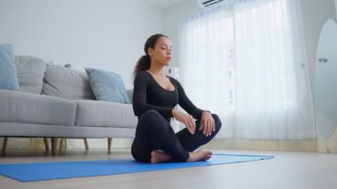 Kadın aydınlık odada yoga yapıyor.