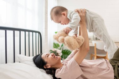 Asyalı bir anne kucağında bebeğini nazikçe yatak odasına atar. Çekici güzel anne, sıcak ve sevgi dolu bir aile ortamını besleyerek, yeni doğmuş bebekle rahat bir odada oynayarak hassas bir anı paylaşıyor..