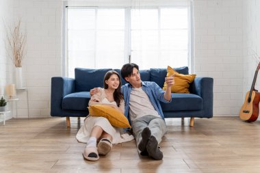 Asyalı genç çift boş zamanlarını birlikte oturma odasında geçiriyorlar. Çekici yeni evli erkek ve kadın yere oturup taşındıktan sonra yeni bir ev bakıyorlar. Evde etkinlik ilişkisi.