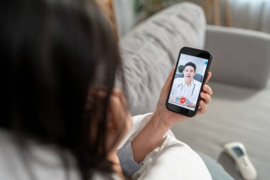 Asyalı genç bayan hasta internette doktorla konuşuyor. Çekici bir doktor, tele sağlık teletıp videosu çekiyor. Evdeki hasta kıza internet danışmanlığı tanısı konuyor..