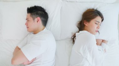 Genç çift yatakta uzanıyor, yüz yüze..