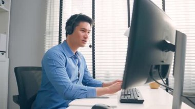 Asyalı çekici iş adamı kulaklık takıyor, ofiste çalışıyor..