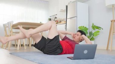 Asyalı yakışıklı aktif genç adam oturma odasında yerde egzersiz yapıyor..
