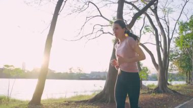Halk parkında koşan Asyalı genç ve güzel spor kadın..