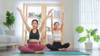 Parlak odada yoga yapan iki kadın.