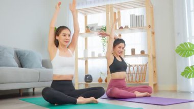 Parlak odada yoga yapan iki kadın.