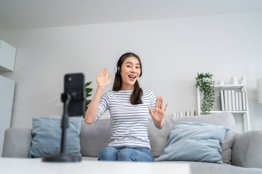 Asyalı çekici kadın evdeki oturma odasında müzikle dans etmekten hoşlanıyor. Güzel bir kadın cep telefonuyla meydan okuma videosu kaydediyor. Sanal bir klipte şarkı söylüyor, hafta sonu evde aktivitelerin keyfini çıkarıyor..