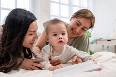 Asyalı lezbiyen çift, erkek çocuklarını evde büyütür ve onlarla ilgilenir. İki kadın anne, sıcak aile ortamında yeni doğmuş bebekleriyle oynarlarken aynı şefkatli anı paylaşıyor.