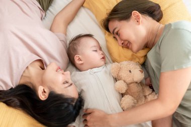 Asyalı lezbiyen çift, erkek çocuklarını evde büyütür ve onlarla ilgilenir. İki çekici kadın anne, yeni doğmuş bebeklerinin yanında uyudukları sıcak aile ortamında şefkatli bir anı paylaşıyorlar.