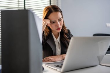 Hüsrana uğramış Asyalı genç iş kadını iş yerinde geç saatlere kadar çalışıyor. Masada oturan çekici bayan çalışan, şirketteki dizüstü bilgisayarda çalışırken stresli ve hayal kırıklığına uğramış hissediyor..